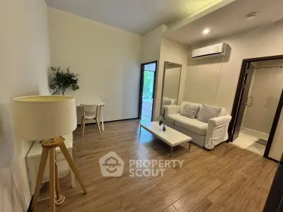 Modern living room with wooden flooring, white sofa, and air conditioning unit.