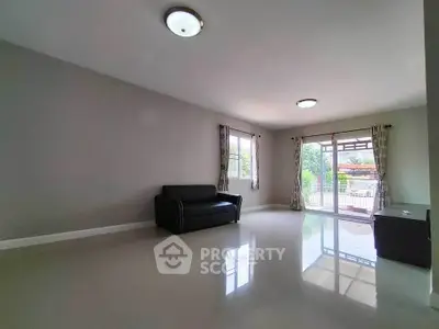 Spacious living room with sleek black sofa and large windows for natural light