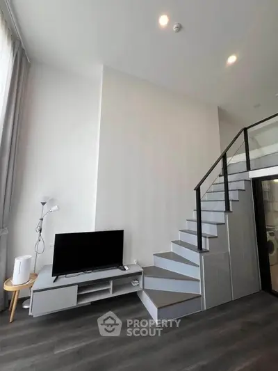 Modern duplex living room with sleek staircase and TV setup