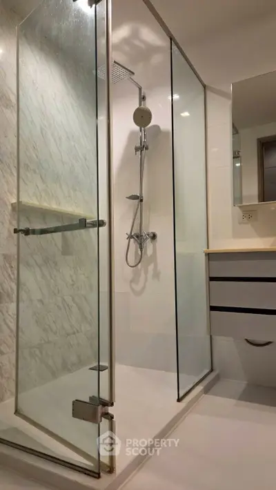Modern bathroom with glass shower enclosure and sleek vanity in contemporary apartment.