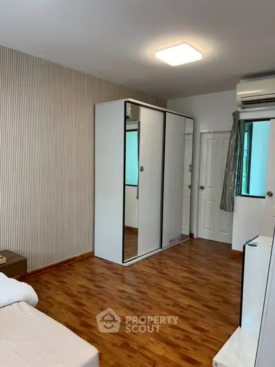 Modern bedroom with mirrored wardrobe and wooden flooring