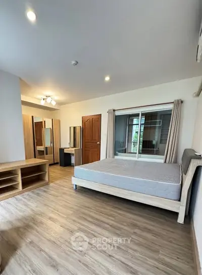 Spacious bedroom with modern furnishings and large window in a stylish apartment.