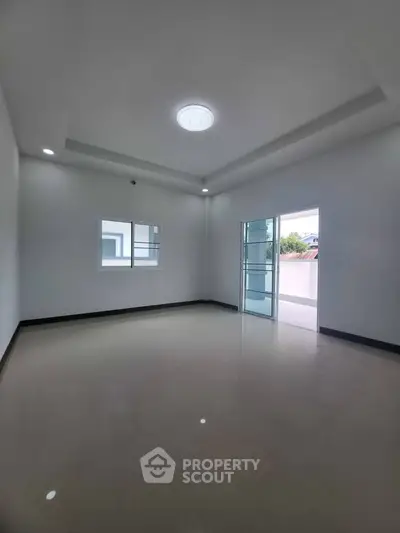 Spacious empty room with large windows and modern lighting, perfect for customization.