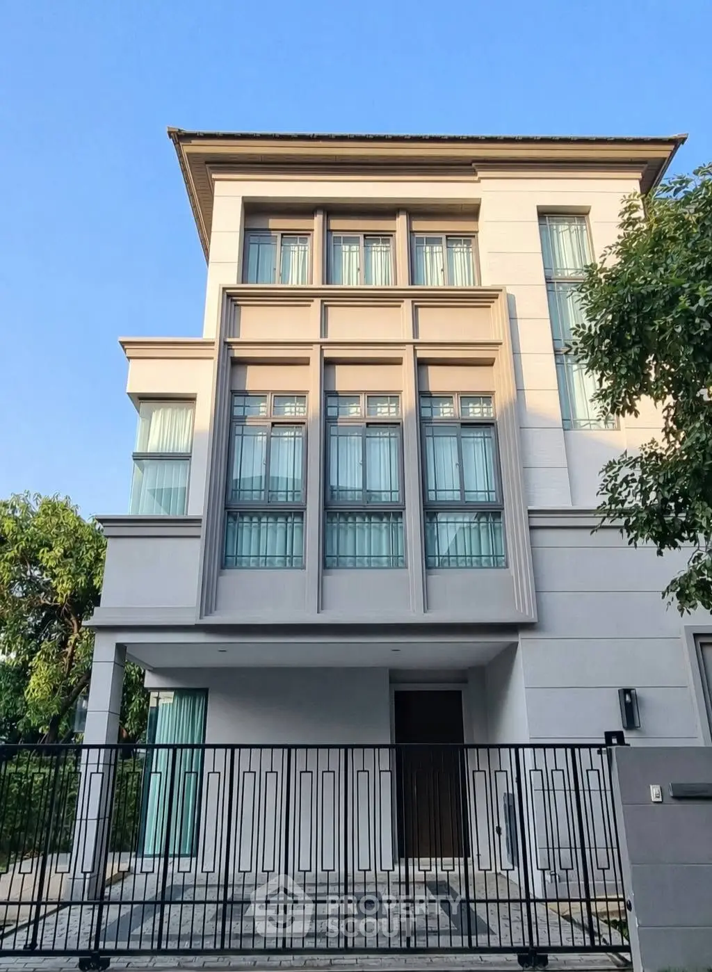 Stunning modern three-story house with large windows and elegant facade in a serene neighborhood.