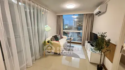 Cozy living room with modern decor and city view, featuring a comfortable sofa and entertainment unit.