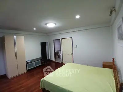 Spacious bedroom with wooden flooring and modern furniture