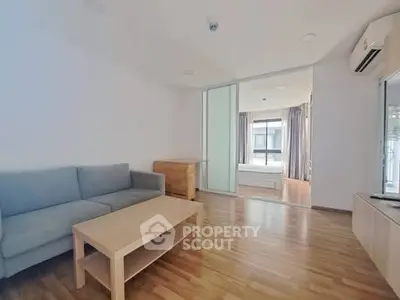 Spacious living room with wooden flooring and modern furniture in a bright apartment.