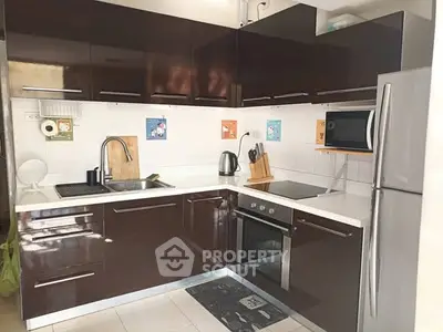 Modern kitchen with sleek dark cabinets, stainless steel appliances, and white countertops.