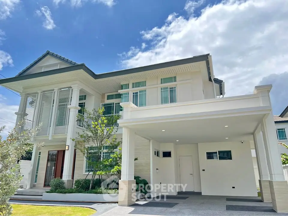 Stunning modern two-story house with lush garden and spacious driveway under a clear blue sky.