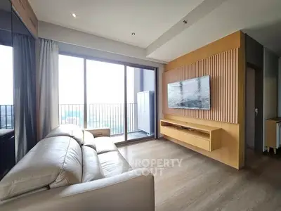 Modern living room with large windows and balcony access, featuring sleek furniture and wooden accents.