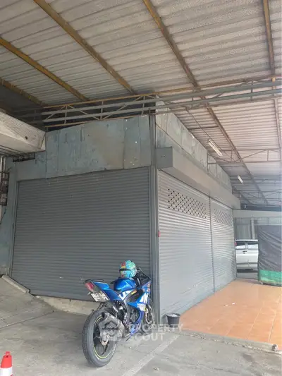 Commercial property with metal shutters and parking area, ideal for business setup.