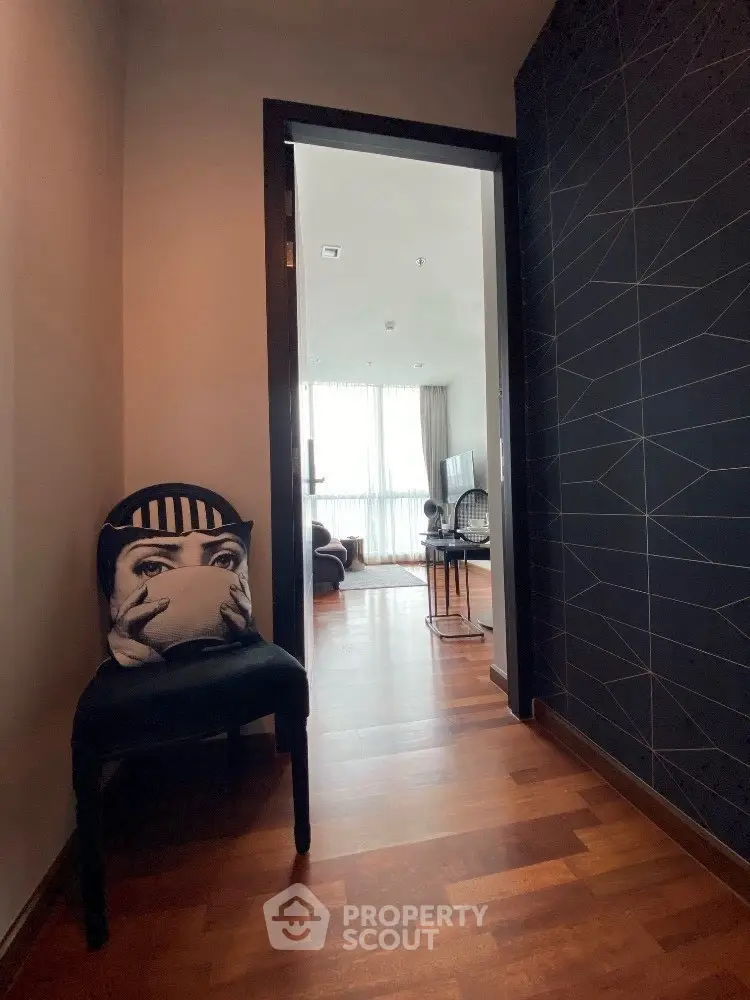 Stylish apartment entrance leading to a modern living room with chic decor and wooden flooring.