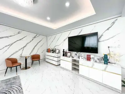 Luxurious modern living room with marble walls and floor, featuring a large TV and elegant furniture.
