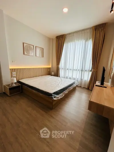 Modern bedroom with wooden flooring and large window with curtains