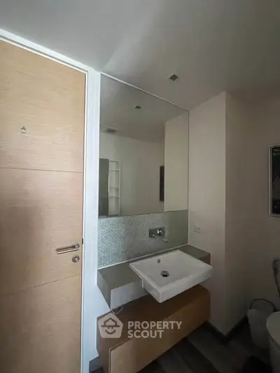 Modern bathroom with sleek sink and large mirror in contemporary apartment.