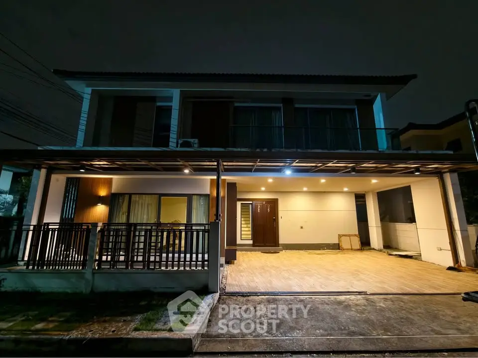 Modern two-story house with spacious carport and stylish exterior lighting at night.