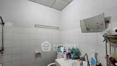 Compact bathroom with essential amenities and tiled walls, featuring a small mirror and storage shelves.