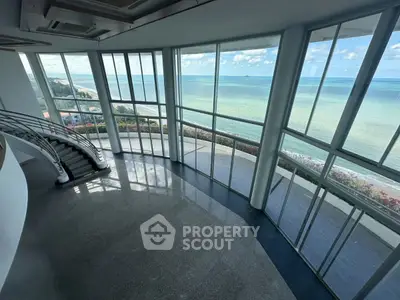 Stunning ocean view from a spacious modern living room with floor-to-ceiling windows and elegant staircase.