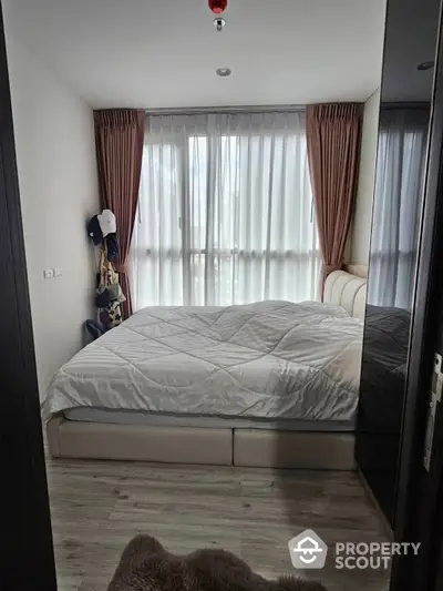 Cozy bedroom with large bed and floor-to-ceiling windows draped in elegant curtains, offering a tranquil retreat in a modern home.