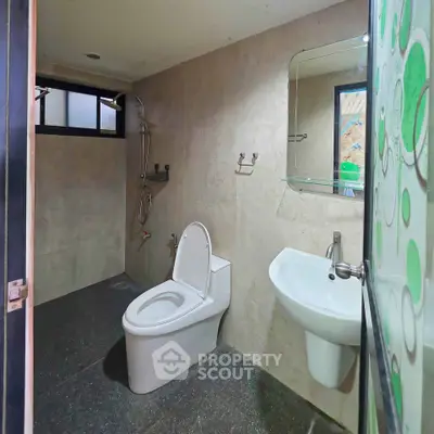Modern bathroom with sleek fixtures and minimalist design, featuring a wall-mounted sink and spacious shower area.