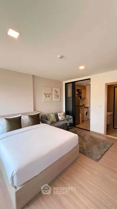 Modern studio apartment with cozy bedroom and open kitchen layout, featuring a washing machine and stylish decor.