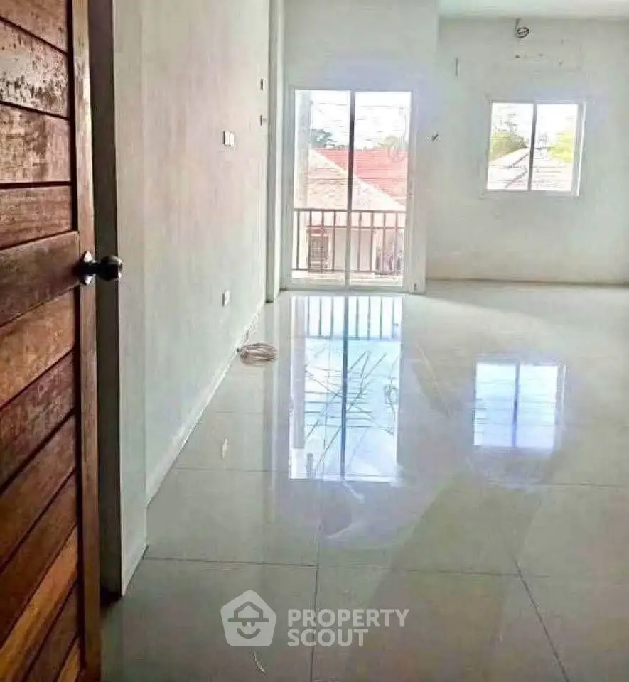 Spacious empty room with glossy tiled floor and balcony view