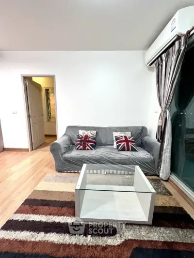 Modern living room with stylish sofa and glass coffee table, featuring floor-to-ceiling windows and wooden flooring.