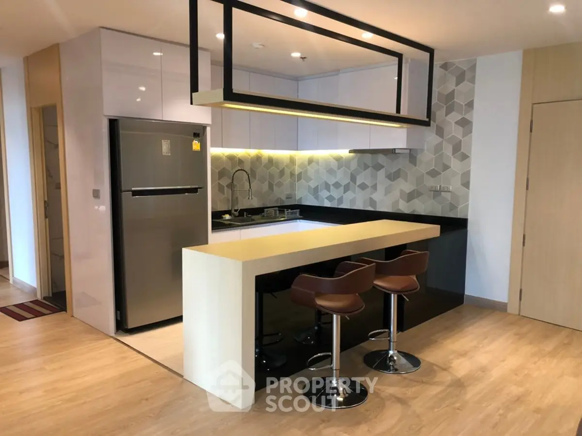 Modern kitchen with sleek design, featuring a breakfast bar and stylish bar stools, perfect for contemporary living.