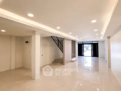 Spacious modern living room with sleek staircase and ample natural light.