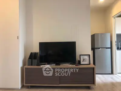 Modern living room with sleek TV stand and stainless steel fridge in open layout.