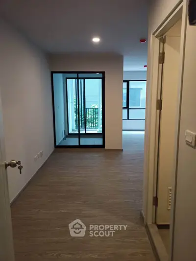 Spacious modern apartment hallway with wooden flooring and large windows