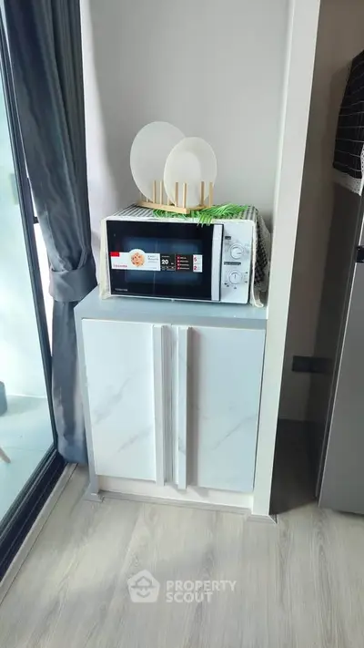 Modern kitchen corner with microwave and stylish cabinet in a bright apartment.