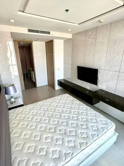 Modern bedroom with sleek design, featuring a wall-mounted TV and stylish decor.