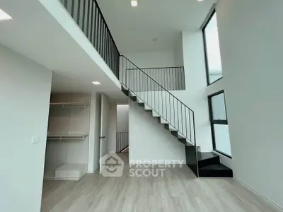 Modern duplex interior with high ceilings and sleek staircase