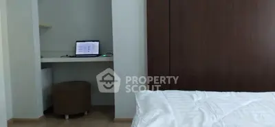 Cozy bedroom with a small study nook featuring a laptop and a comfortable stool.