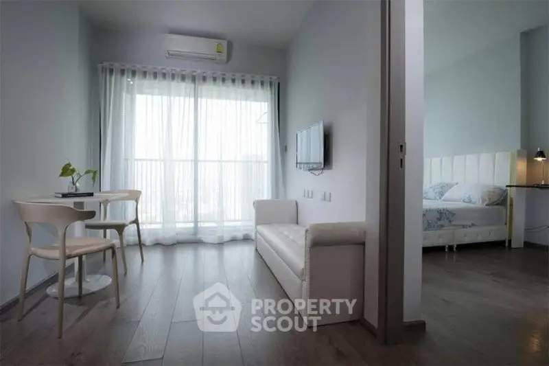 Modern apartment with open living room and bedroom, featuring sleek furniture and natural light.