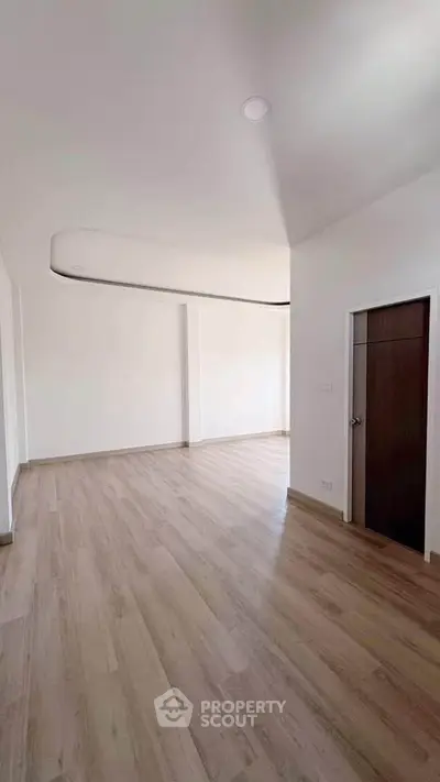 Spacious modern living room with sleek wooden flooring and minimalist design.