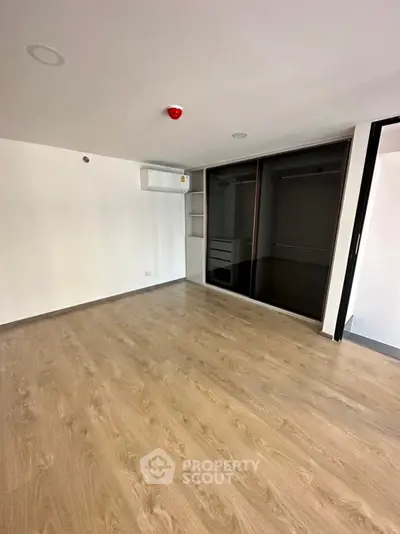 Spacious empty room with wooden flooring and built-in closet in modern apartment.