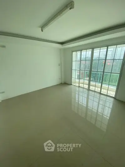 Spacious empty room with large windows and balcony access, perfect for customization.
