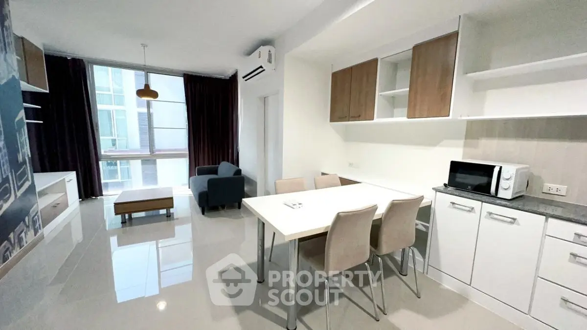 Modern open-plan living room and kitchen with sleek furniture and large window