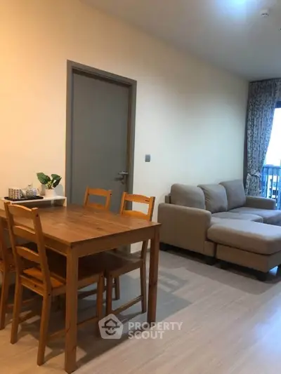 Cozy living room with wooden dining set and comfortable sofa, perfect for relaxation and entertaining.