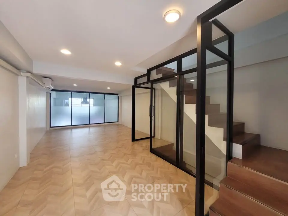 Spacious modern interior with glass partitions and wooden staircase