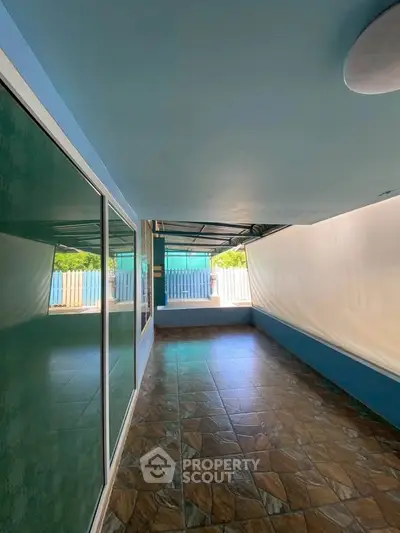 Spacious covered balcony with tiled flooring and glass doors