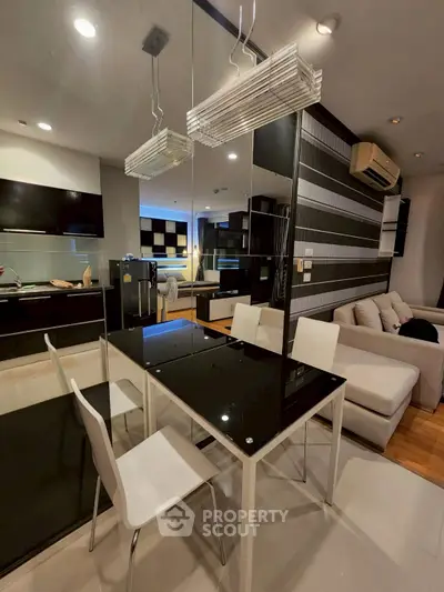 Modern open-plan living and dining area with sleek black and white decor and contemporary lighting.