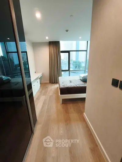 Modern bedroom with large windows and wooden flooring in a high-rise apartment.