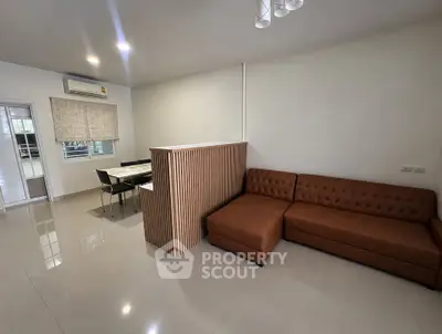 Modern living room with stylish brown sofa and dining area, featuring sleek design and ample natural light.