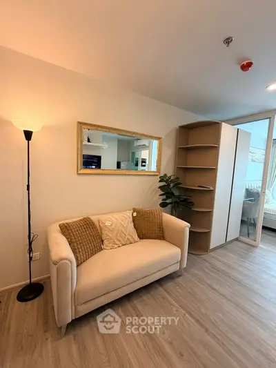 Modern living room with cozy sofa, stylish mirror, and elegant shelving unit in a bright apartment.