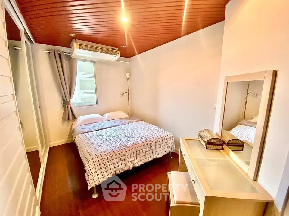 Cozy bedroom with wooden ceiling and mirrored closet in modern apartment