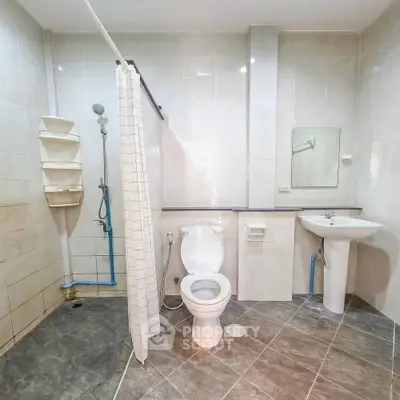 Spacious bathroom with modern fixtures and tiled flooring, featuring a shower and toilet.