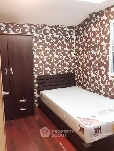 Cozy bedroom with unique circular patterned wallpaper and wooden flooring